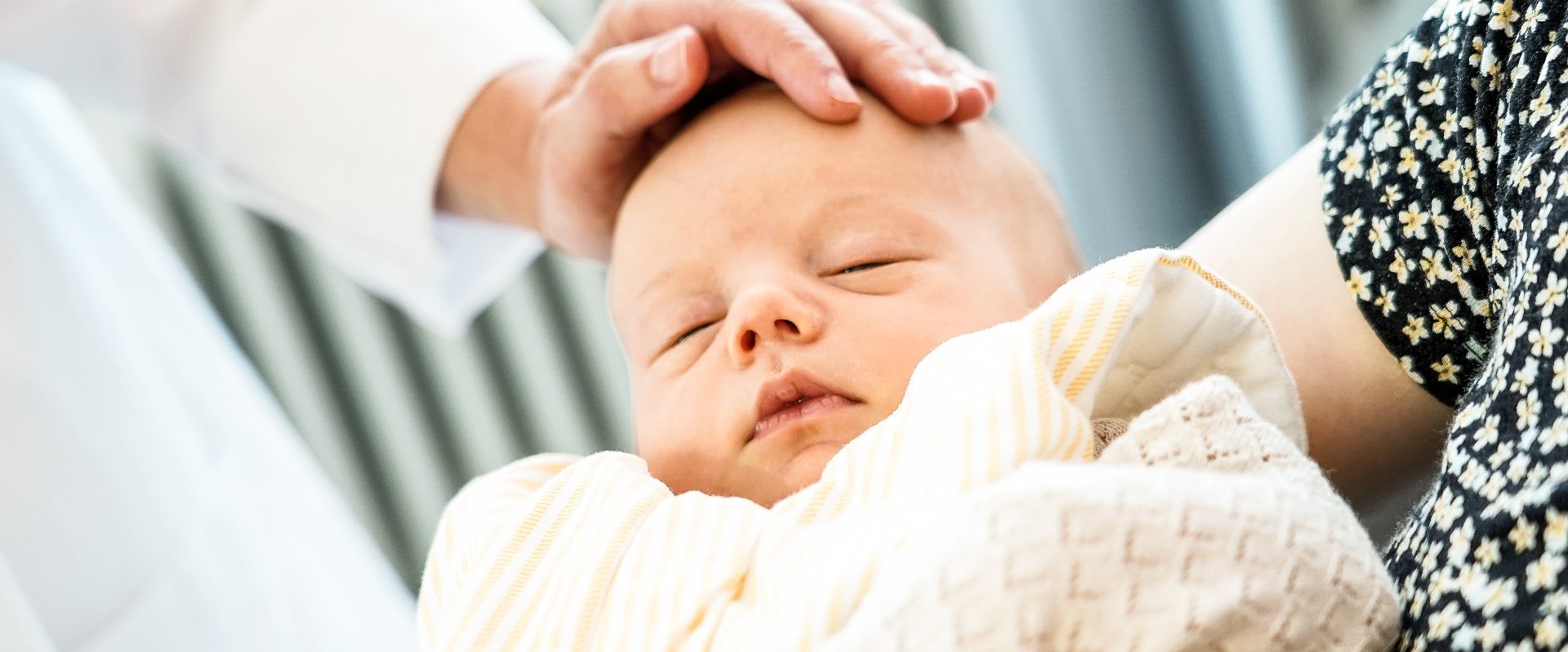 Hand berührt Baby nach der Geburt am Kopf