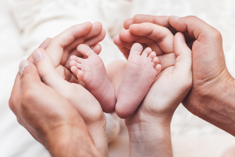 Abbildung: Grusskarten Geburt - Babyfüße werden von Elternhänden umschlossen